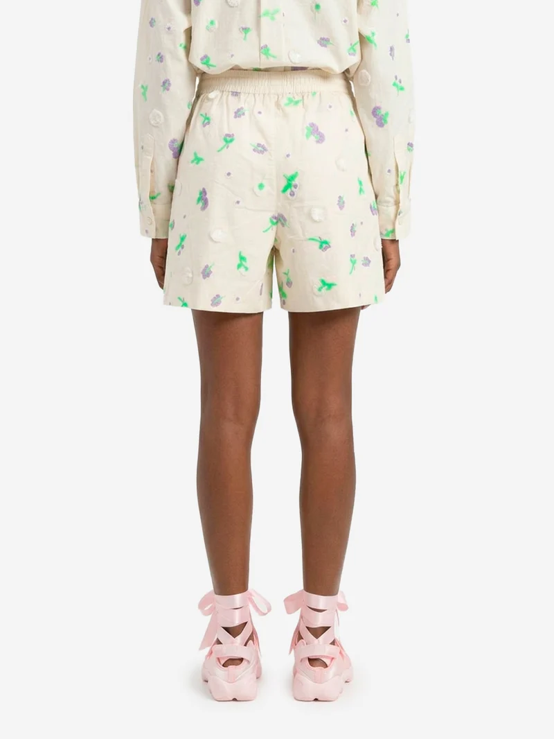 Pantaloncini bianchi con decorazioni floreali in paillettes, strass e perline viola e verdi